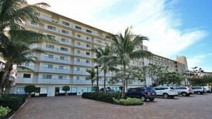 Un hotel de varios pisos con estacionamiento y palmeras.