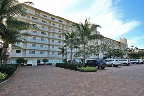 A multi-story hotel with a parking lot and palm trees.