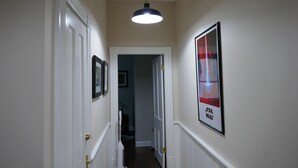 A hallway with white walls, a framed poster of a Star Wars character, and a hanging light fixture. - Spacious home in the Historic District. Sleeps 8. Free Parking (Savannah)