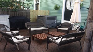 An outdoor patio with wicker furniture, a barbecue grill, and a covered grill. - Spacious home in the Historic District. Sleeps 8. Free Parking (Savannah)
