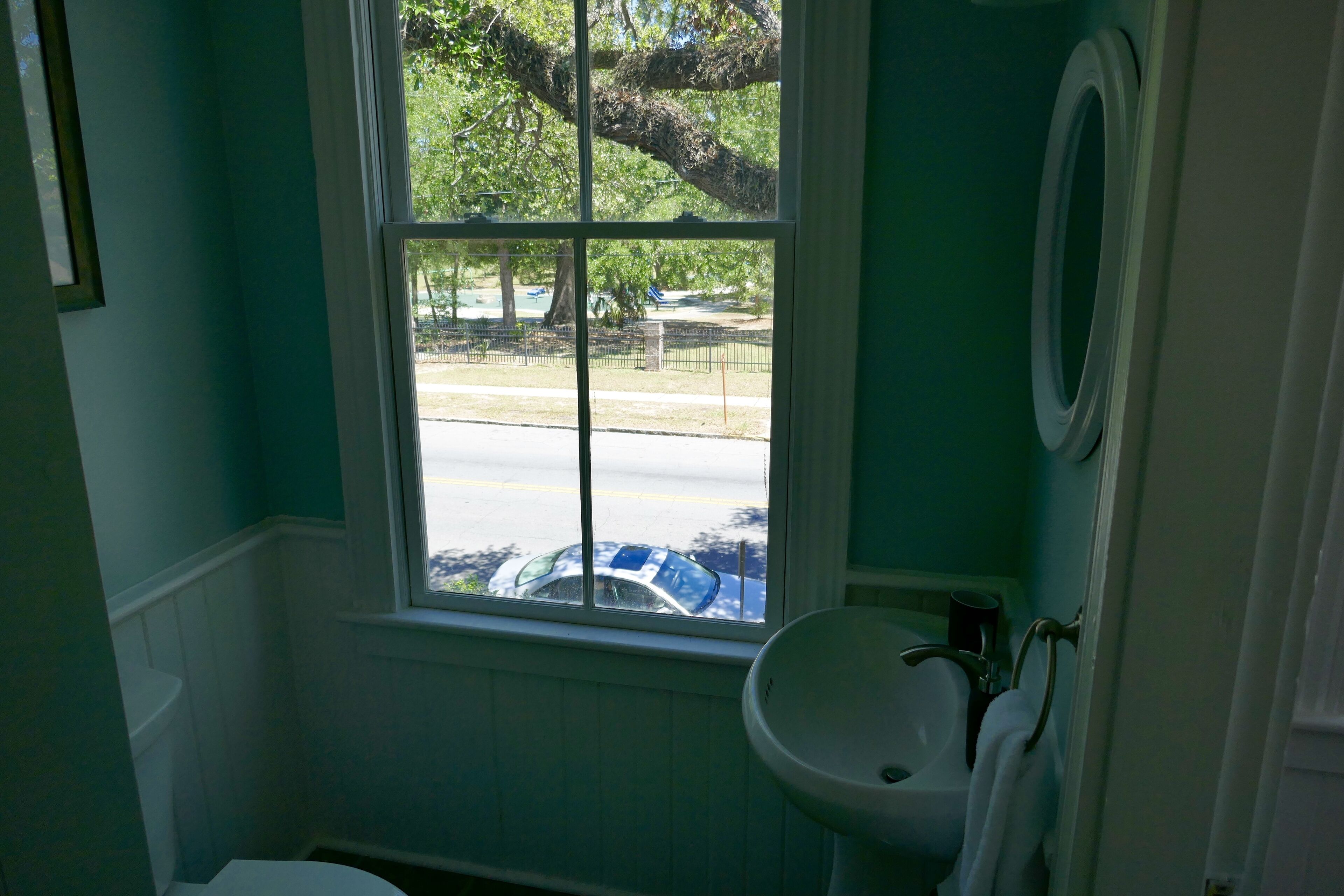 A bathroom with a window, sink, and toilet.