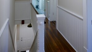 A hallway with a wooden floor, white wainscoting, a framed certificate on the wall, and a door at the end. - Spacious home in the Historic District. Sleeps 8. Free Parking (Savannah)