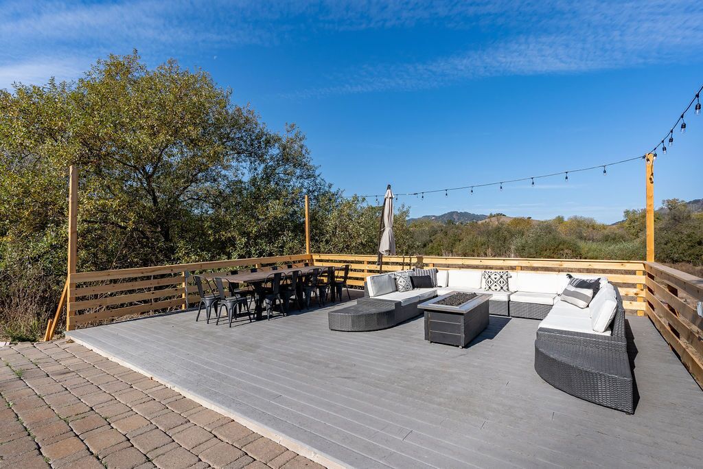 An outdoor patio with a wooden deck, wicker furniture, and string lights.
