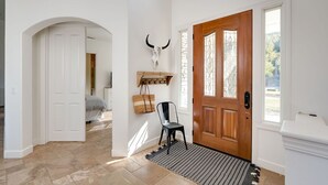 A hallway with a wooden door, a bull skull decoration, a chair, and a rug. - Avila Valley Luxury Estate with Pickleball Court (San Luis Obispo)