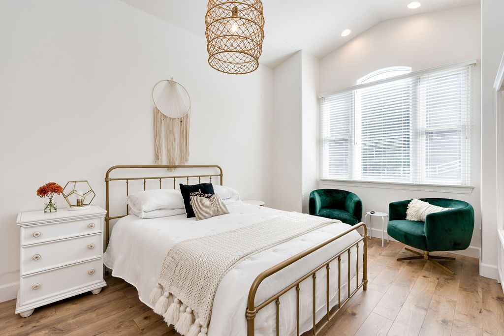 A bedroom with a bed, bedside table, dresser, and a window with blinds.