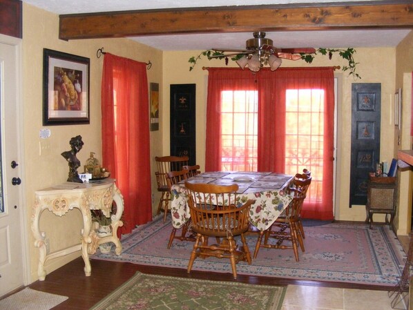 A dining room with a wooden table, chairs, and a chandelier.