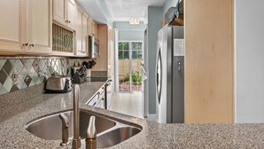 Una cocina con encimeras de granito, electrodomésticos de acero inoxidable y armarios de madera.