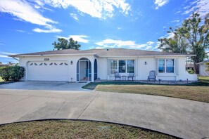 A single-story house with a garage, a covered patio, and a small lawn area. - 5 bedroom, South facing, FREE heated salt water pool, with Direct Gulf access (Cape Coral)