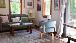 Ein gemütliches Wohnzimmer mit einer Couch, einem kleinen Tisch, einem blauen Sessel und einem gemusterten Teppich.