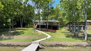 Une propriété située au bord de la rivière, dotée d’un quai, d’une pelouse et d’un bâtiment à deux étages avec un balcon.