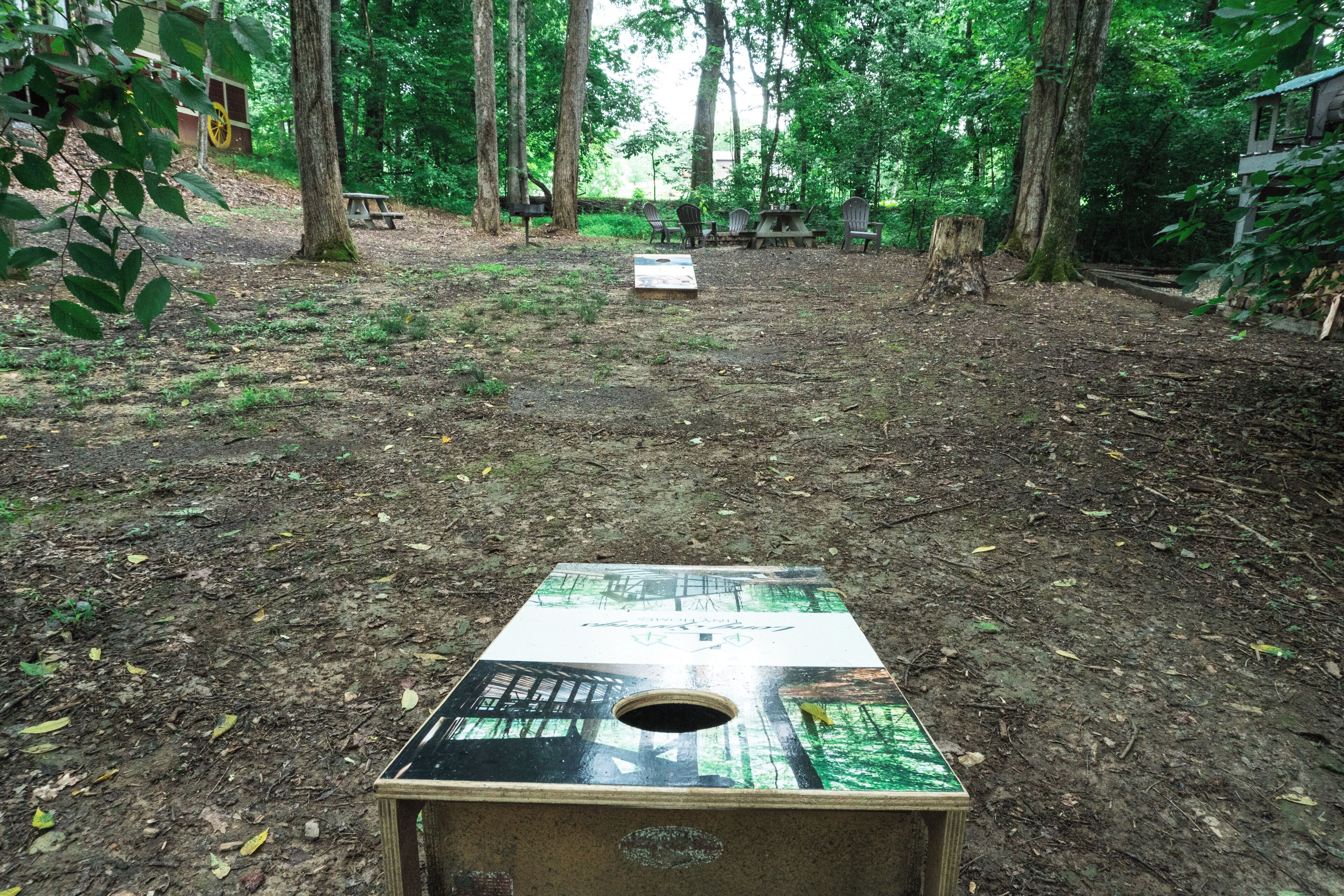 Un jeu de société en bois installé dans un espace boisé, avec une table de pique-nique et des chaises.