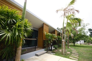 A modern house with a wooden facade, a black door, and a concrete pathway leading to the entrance. - Phumi Resort (Thep Krasattri)