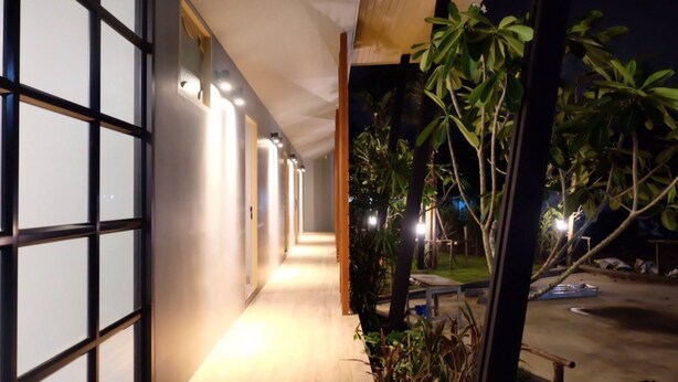 A corridor with a wooden floor leading to a door with glass panels. - Phumi Resort (Thep Krasattri)
