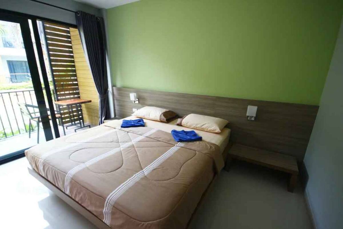 A hotel room with a bed, a bench, and a view of the outside.