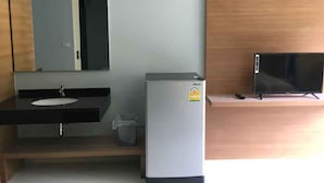 A bathroom with a sink, mirror, and a small refrigerator. - Phumi Resort (Thep Krasattri)