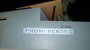 A sign for PHUMI RESORT with a modern design and Thai script. - Phumi Resort (Thep Krasattri)