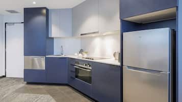 A modern kitchen with blue cabinetry, stainless steel appliances, and a tiled backsplash.