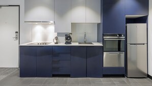 Una cocina moderna con horno empotrado, refrigerador y cafetera sobre la encimera.