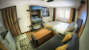 A compact room with a bed, a small table, a mirror, and a wardrobe. - Concept House (Ankara)