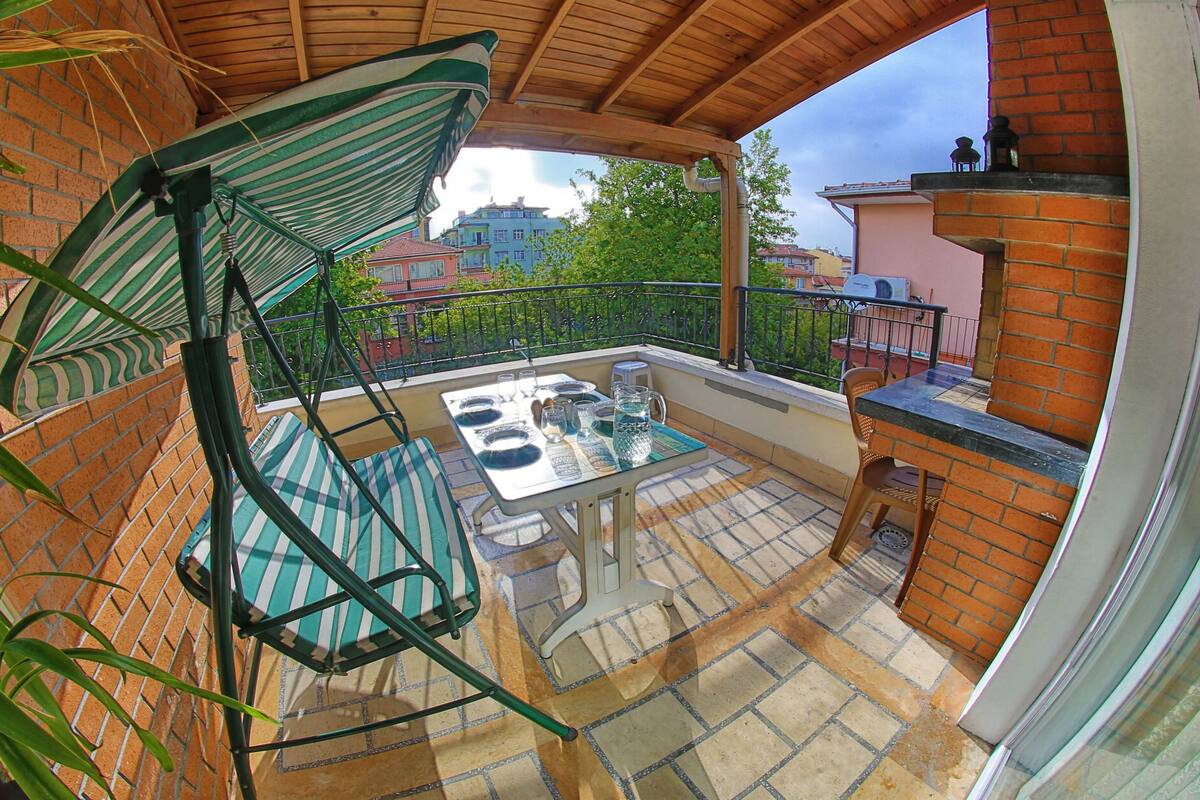 A balcony with a table, chairs, and a hanging umbrella.