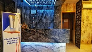 A reception desk with a marble-like design, a digital screen, and a signboard with text. - Concept House (Ankara)