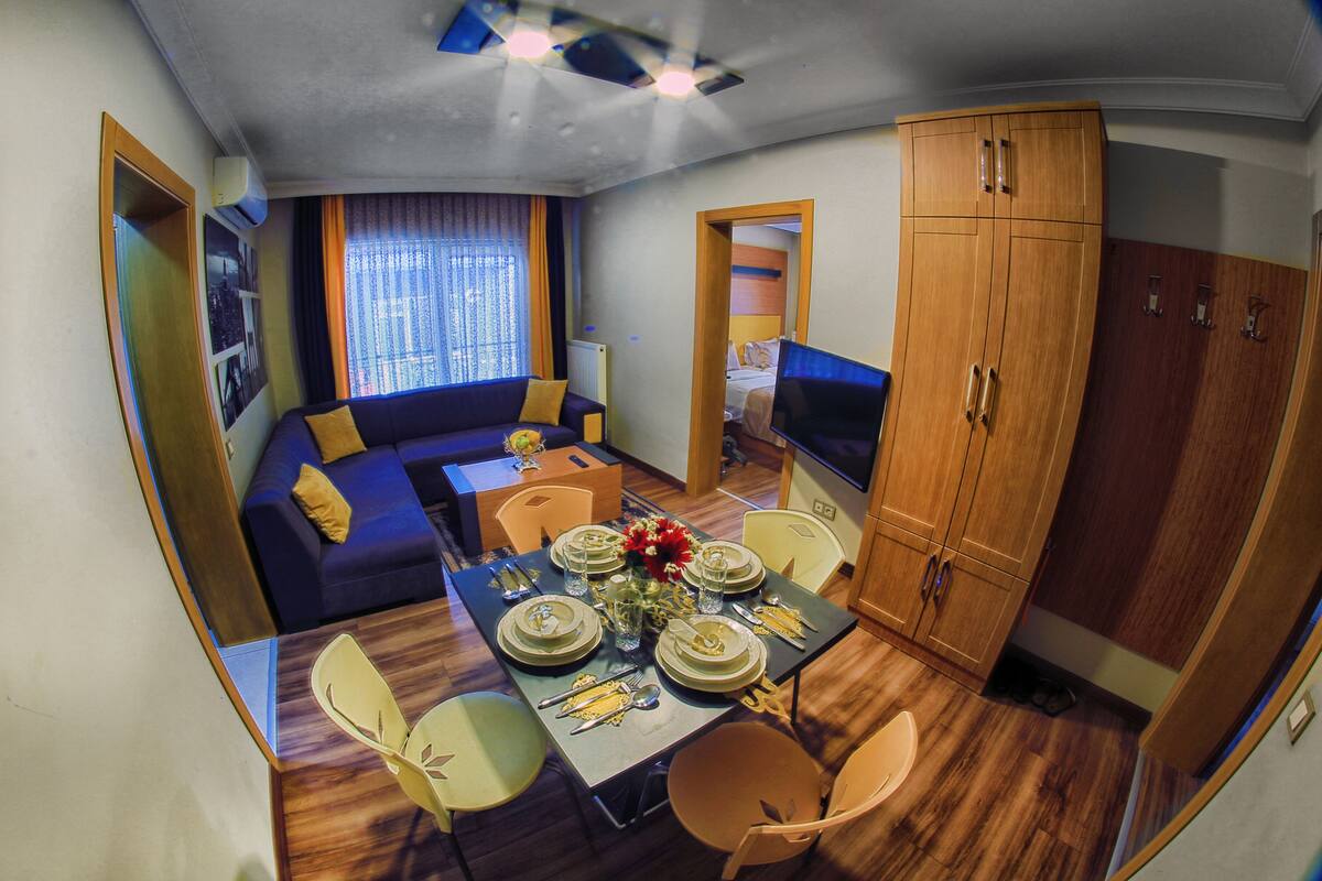 A compact living space with a dining area, sofa, TV, and wardrobe.