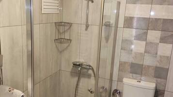 A bathroom with a glass-enclosed shower, a toilet, and a sink.