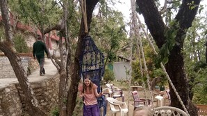 A rustic outdoor setting with a swing set, stone walls, and a dirt ground. - Trinetra Orchards (Dhari)