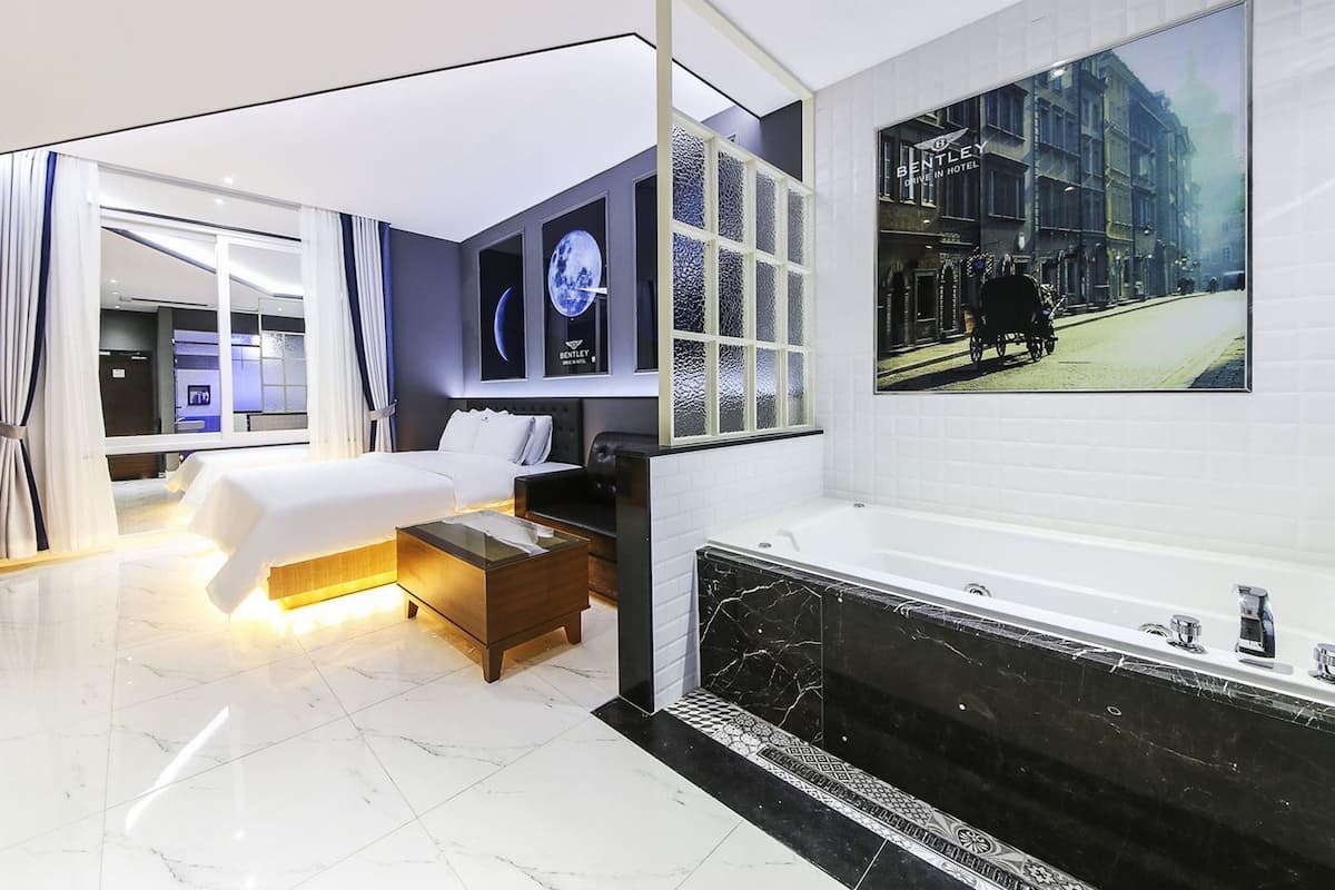 Ein modernes Hotelzimmer mit einem großen Bett, einer Sitzecke, einer Badewanne und Blick auf die Stadt.