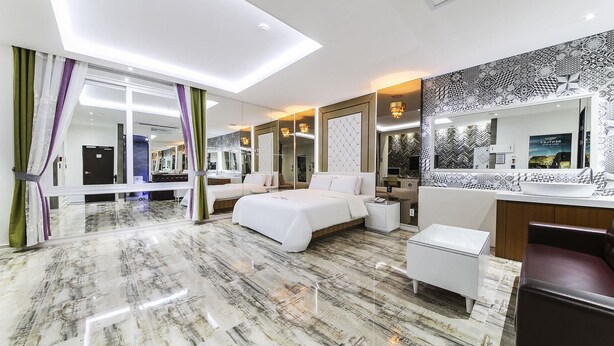 Habitació d'hotel moderna amb un llit gran, zona de seients, tocador i bany.
