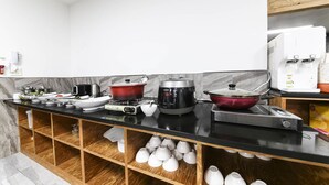 Cuina moderna amb taulell negre, una cafetera, una cocedora d'arròs i una olla vermella.