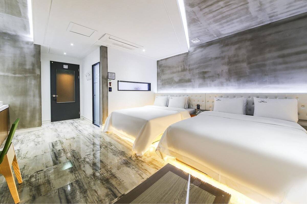 Ein modernes Hotelzimmer mit zwei Betten, einem großen Fenster und einem Marmorboden.