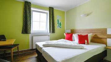 Une chambre d’hôtel avec un lit, un bureau et une fenêtre avec des rideaux.