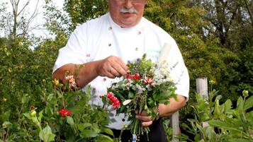 Une personne vêtue d’une blouse de chef blanche tenant un bouquet de fleurs.