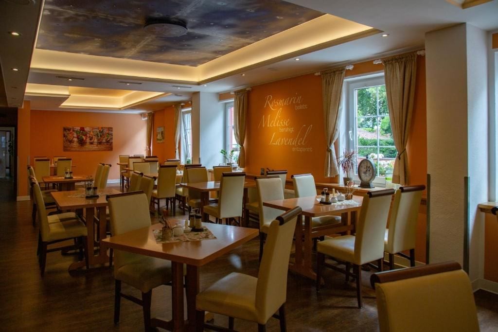 Ein Restaurant mit mehreren Tischen und Stühlen, einer Decke mit einem außergewöhnlichen Design und einer Wand mit einer Speisekarte.