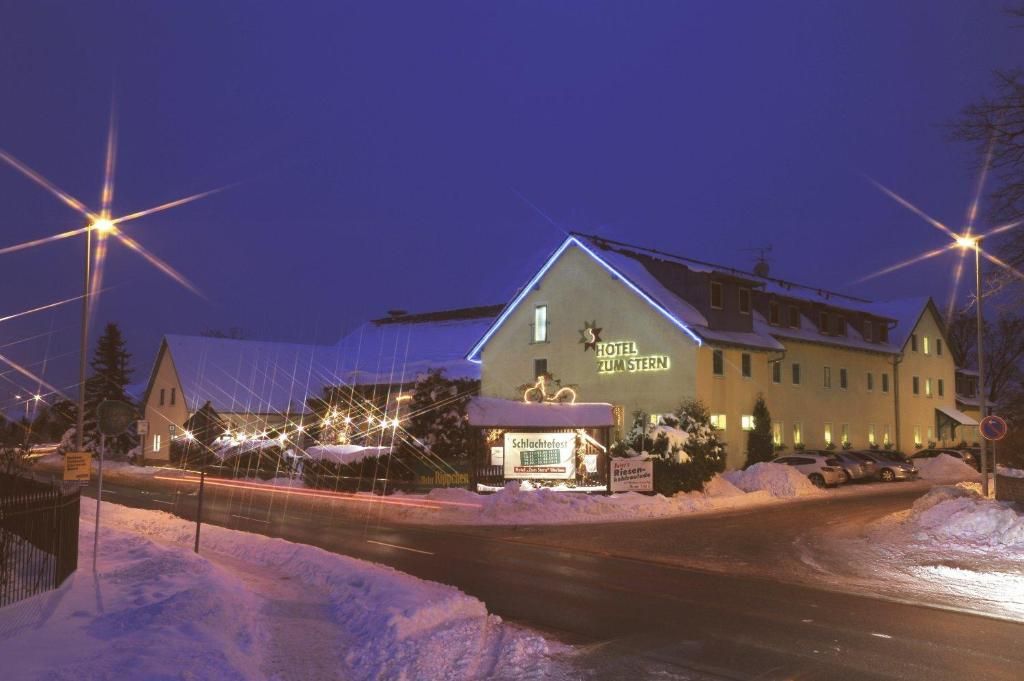 A hotel with a sign reading 'HOTEL ZUM STERN' at night, surrounded by snow and illuminated by street lights.