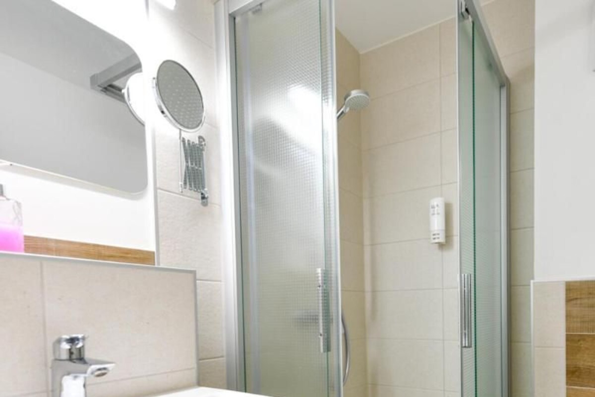 A modern bathroom with a glass-enclosed shower, a sink with a mirror, and a toilet.