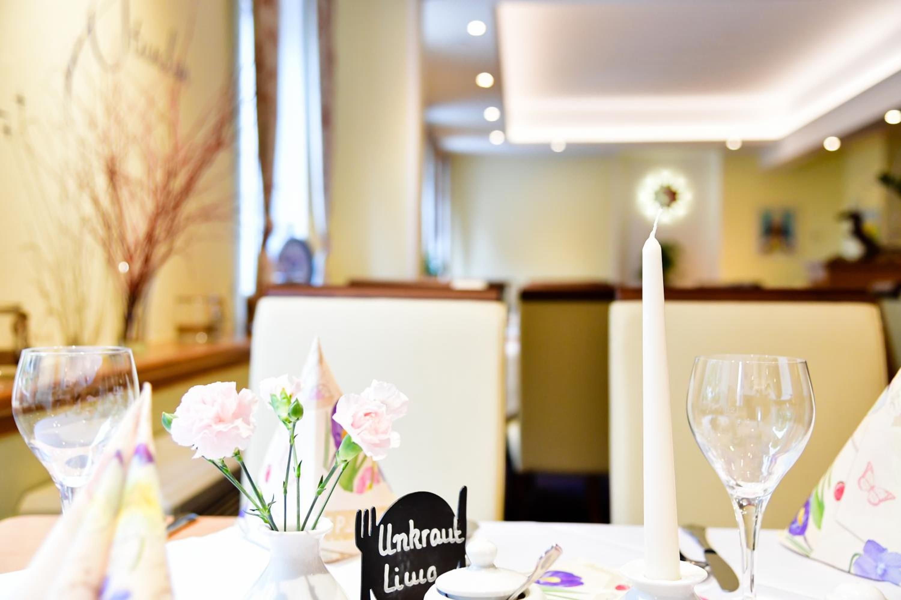 Una mesa dispuesta con una vela, un florero con flores y un letrero que dice 'Unkraut Liua'.