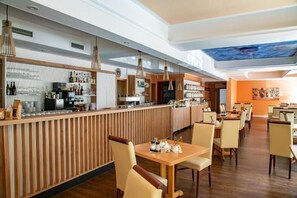 Un restaurante con zona de bar, paneles de madera y un mural en el techo.