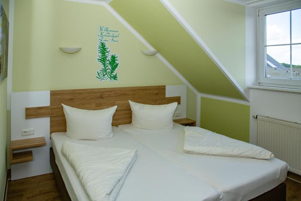 A bedroom with a sloped ceiling, a bed with white bedding, a wooden headboard, bedside tables, and a window with a view.