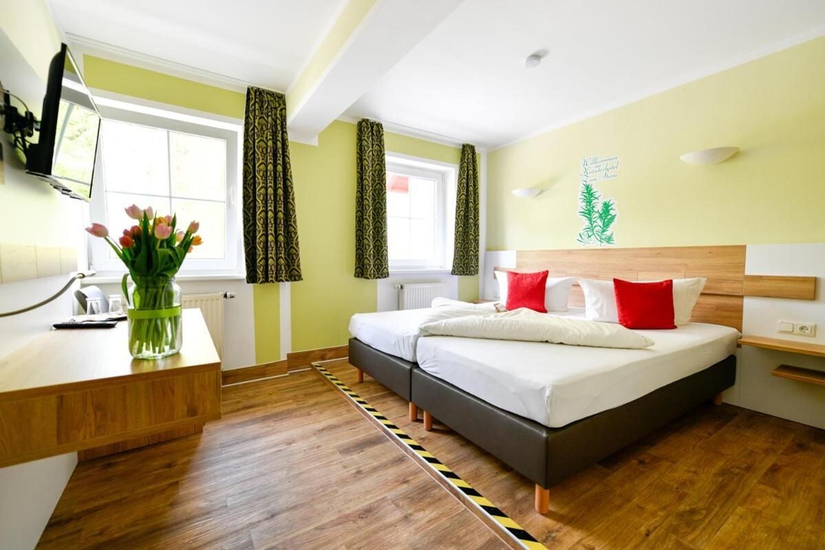 A hotel room with a bed, bedside tables, a desk, and a window with curtains.