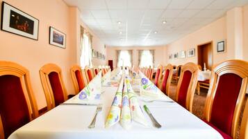 A long table set for a formal event with floral tablecloths and silverware.