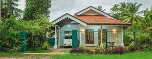 A single-story house with a red-tiled roof, surrounded by lush greenery and palm trees. - Winee's Lodge (Marawila)
