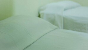 Una habitación con una cama cubierta de sábanas blancas.