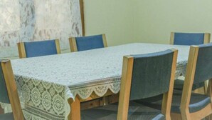 Una mesa de comedor con mantel de encaje, rodeada por seis sillas de madera con cojines azules.