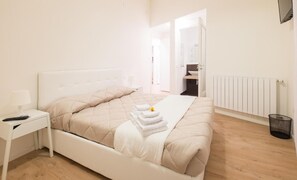 A neatly arranged bedroom with a bed, bedside table, and a view of the bathroom.