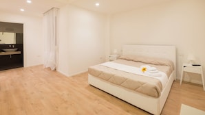 A modern bedroom with a large bed, a bedside table, a nightstand, and a bathroom visible through an open door. - Dante 58 (Palermo)