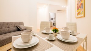 A dining area with a table set for four, a sofa, and a kitchen in the background. - Dante 58 (Palermo)