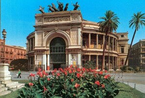 A historic building with a grand archway and statues on top.