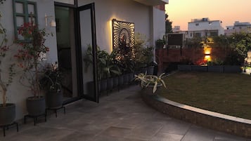 A modern building with a tiled patio, potted plants, and a decorative wall.